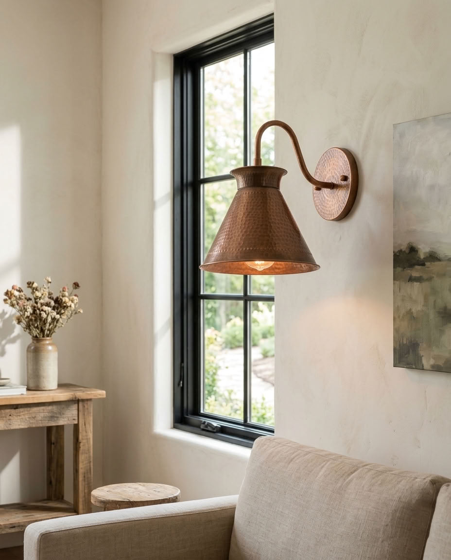 Hammered copper cone wall sconce with curved arm and warm ambient light — view 1