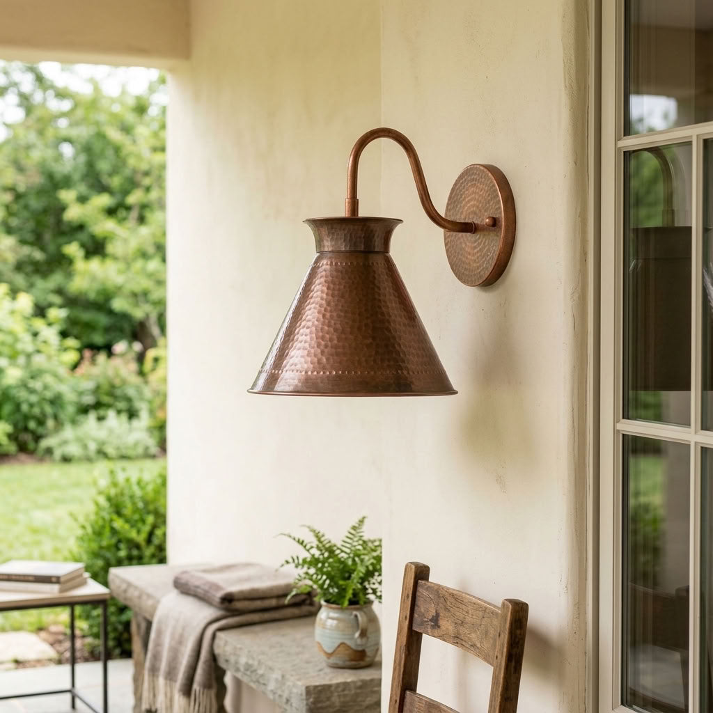 Hammered copper cone wall sconce with curved arm and warm ambient light — view 3