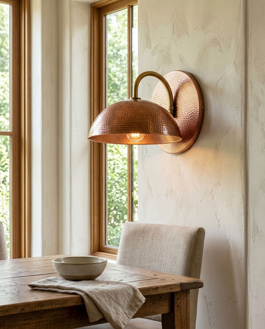 Hammered copper dome wall sconce with curved arm and warm ambient light — view 1