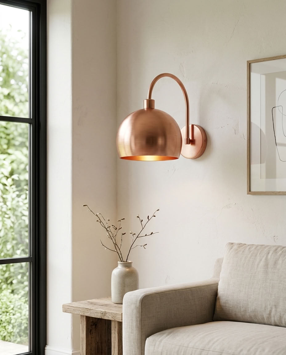 Modern smooth copper dome wall sconce with arched arm and warm light — view 1