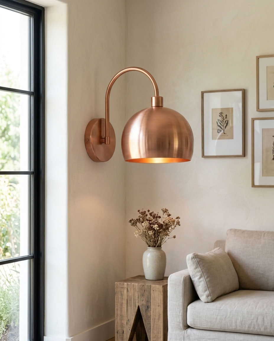 Modern smooth copper dome wall sconce with arched arm and warm light — view 2